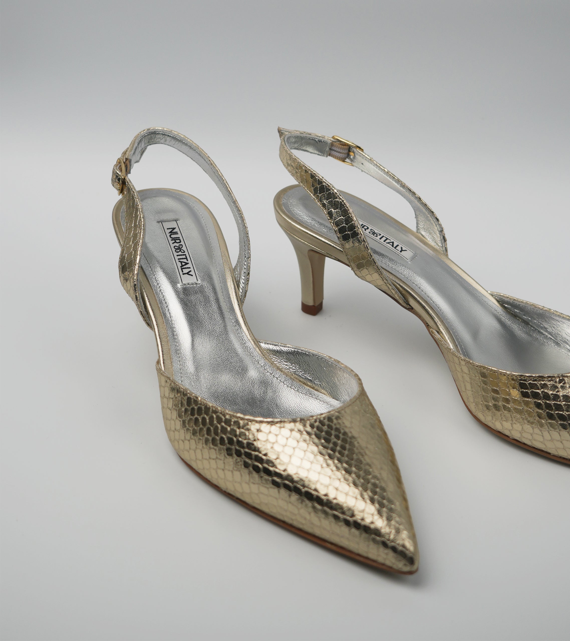 Gold high-heeled shoes with 'Jimmy Choo' branding on a light gray background #color_venezia gold