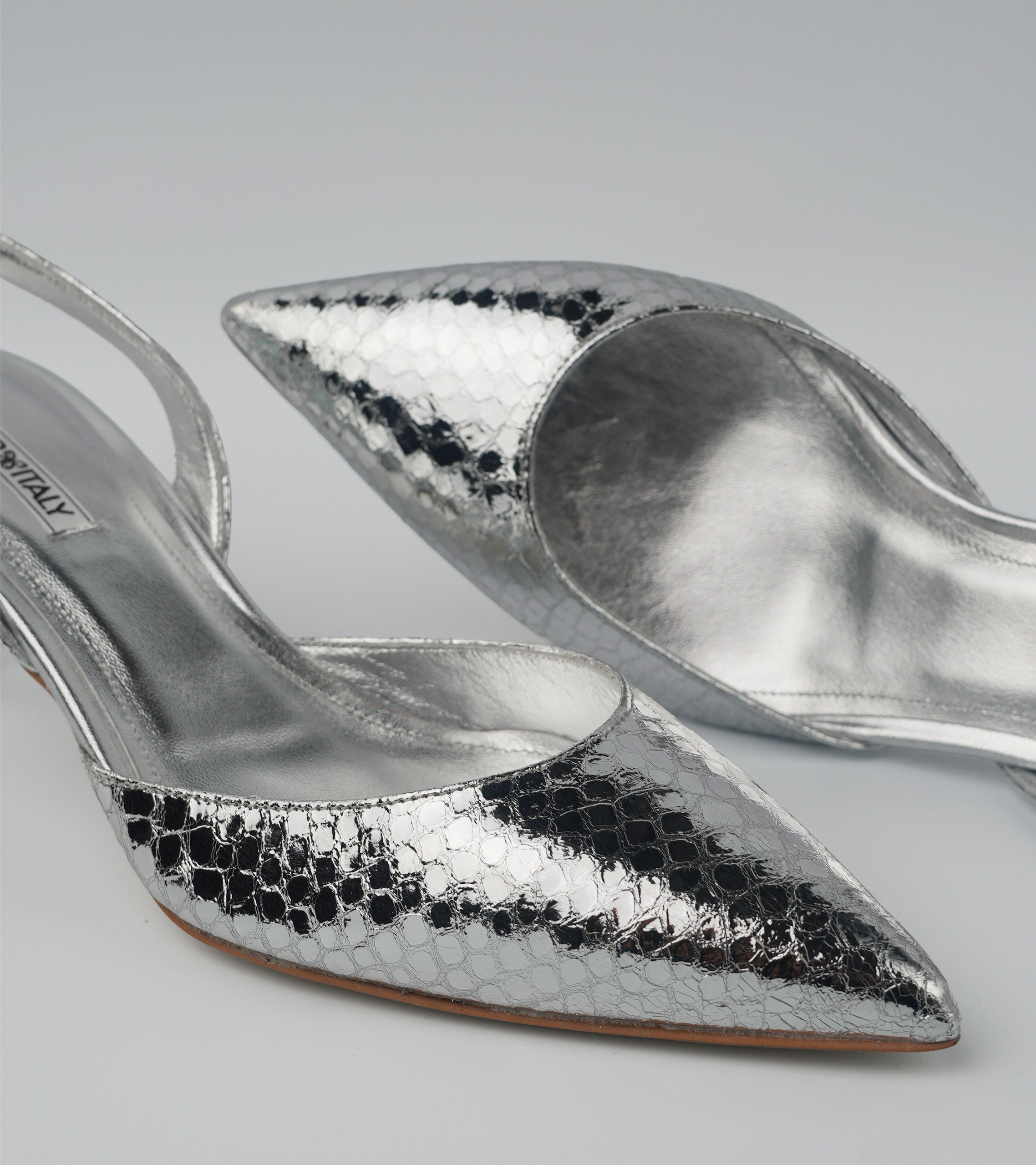 Silver high-heeled shoes with snake print on a light gray background #color_napoli silver