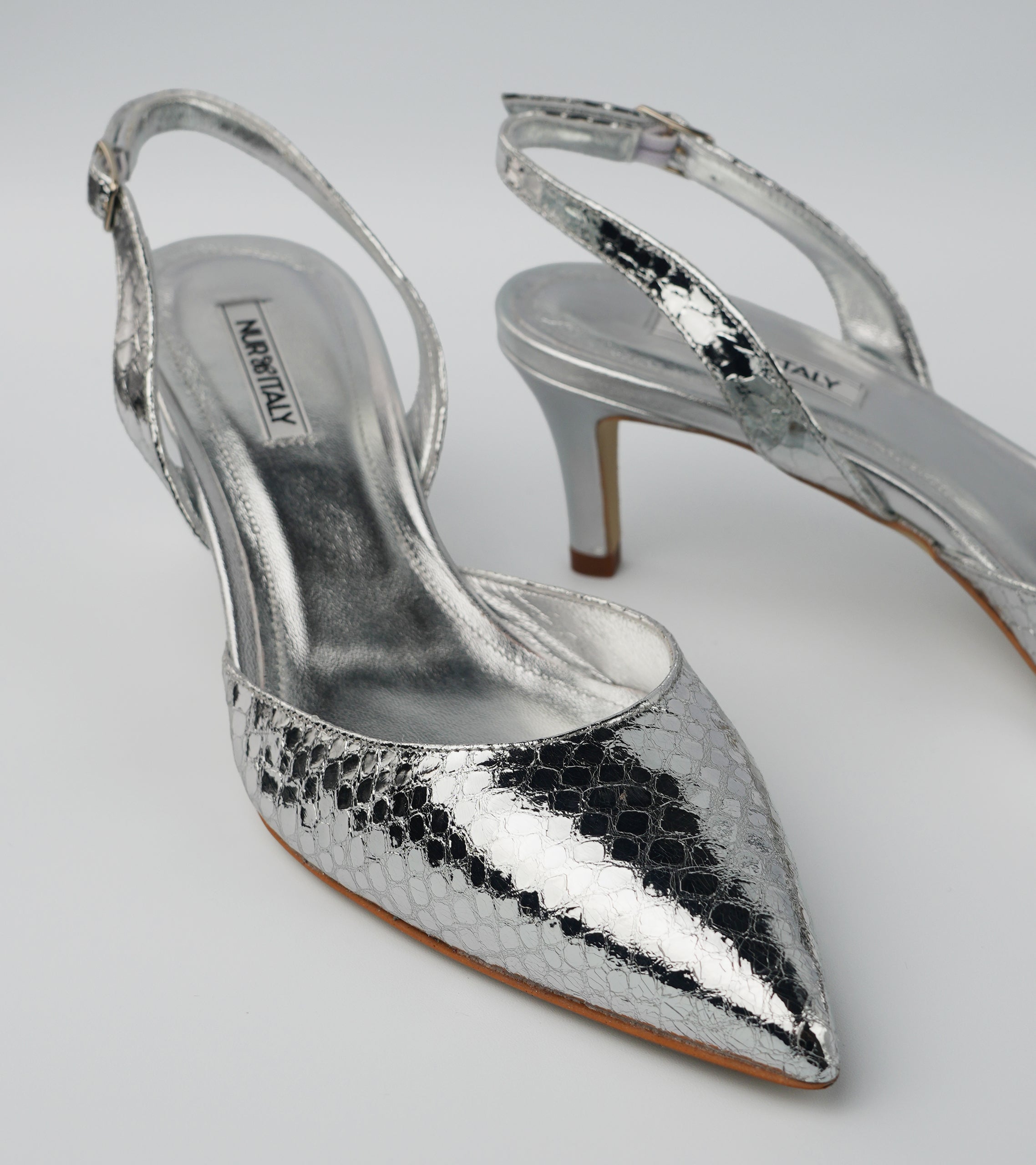 Silver high-heeled shoes with snake print on a light gray background #color_napoli silver