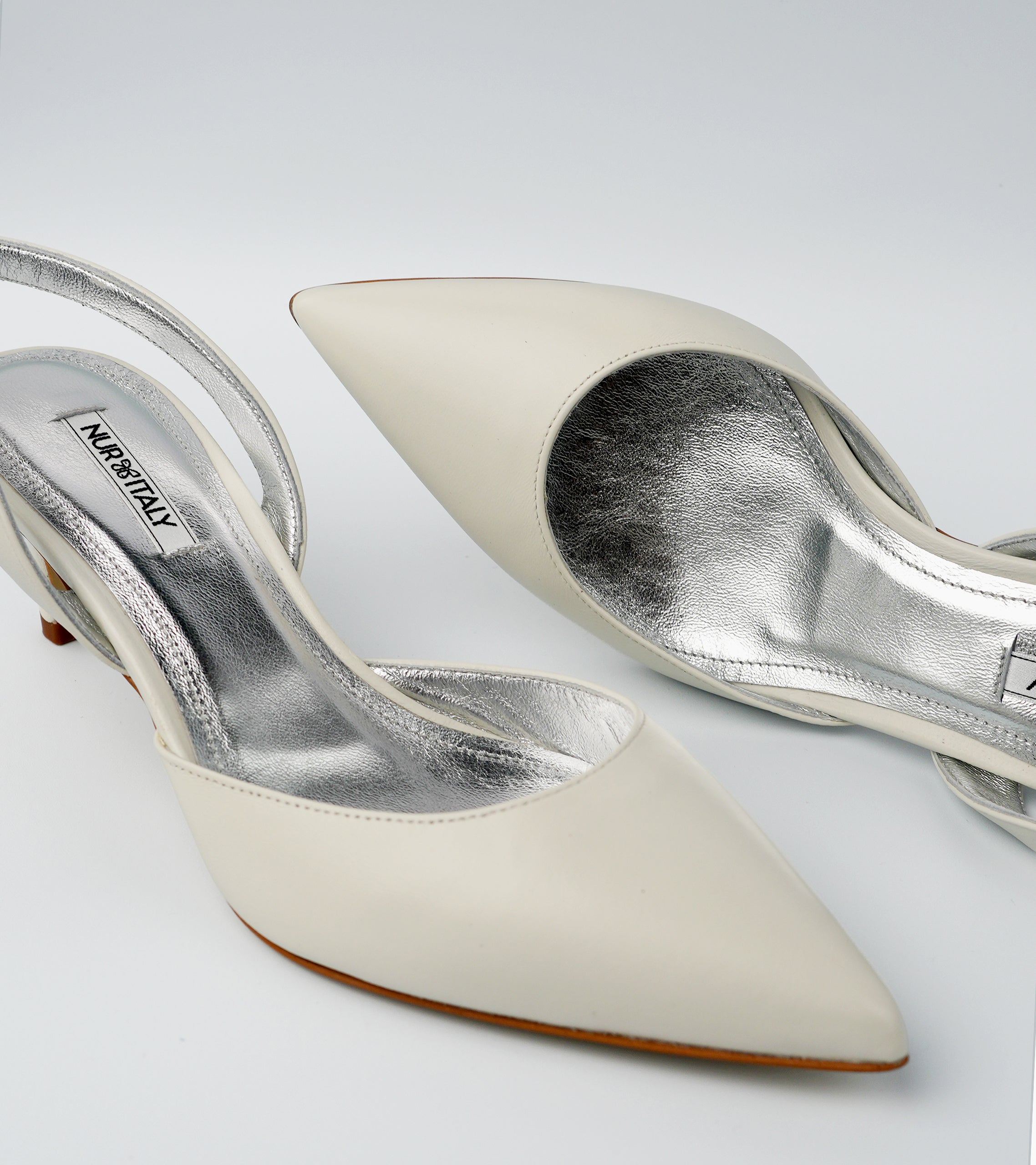 Pair of white high-heeled shoes with silver soles on a light gray background #color_amalfi white
