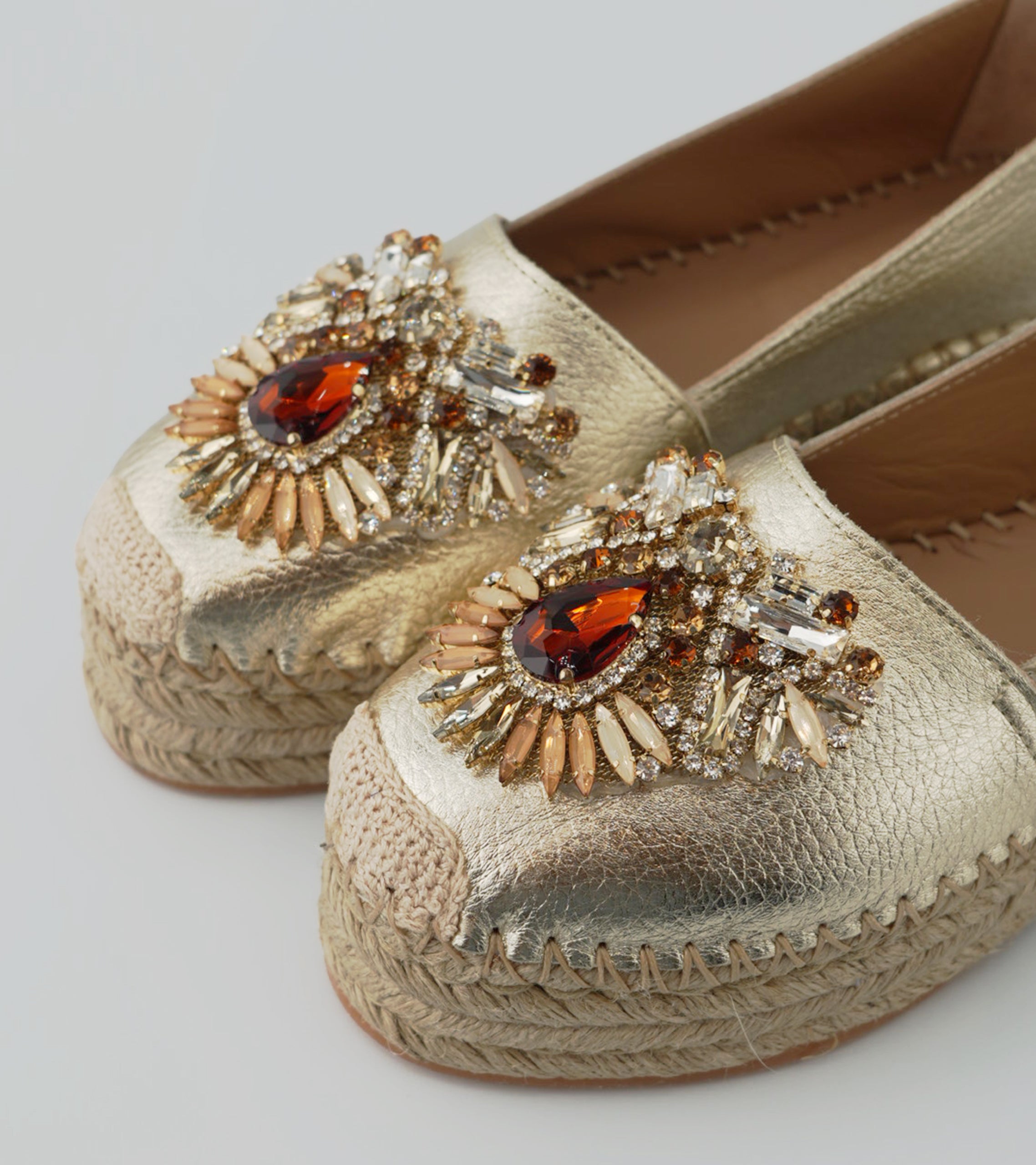 Gold espadrille shoes with decorative brooches on a light gray background #color_venezia gold