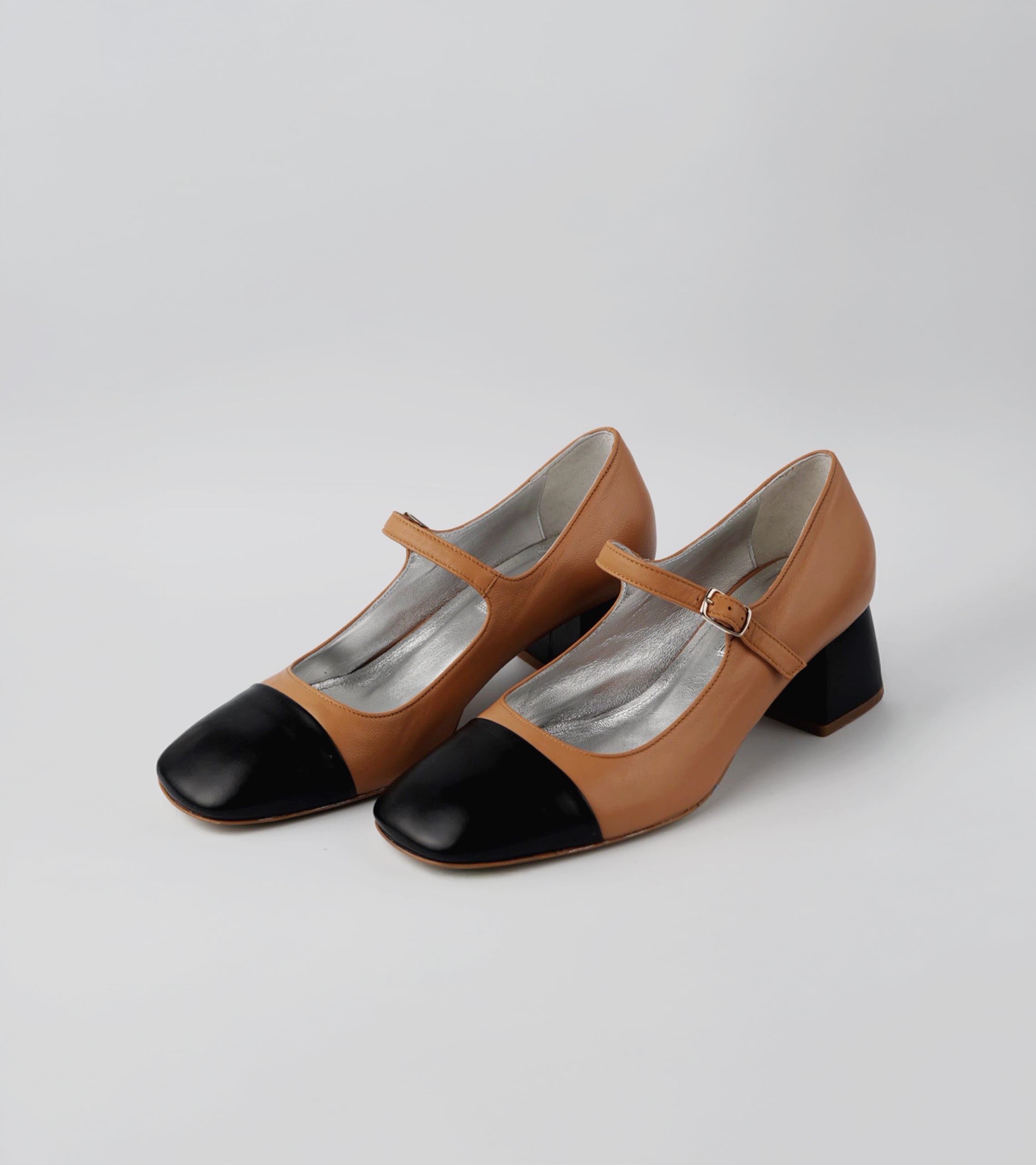 Pair of brown and black shoes with a strap on a light gray background #color_palermo tan milano black