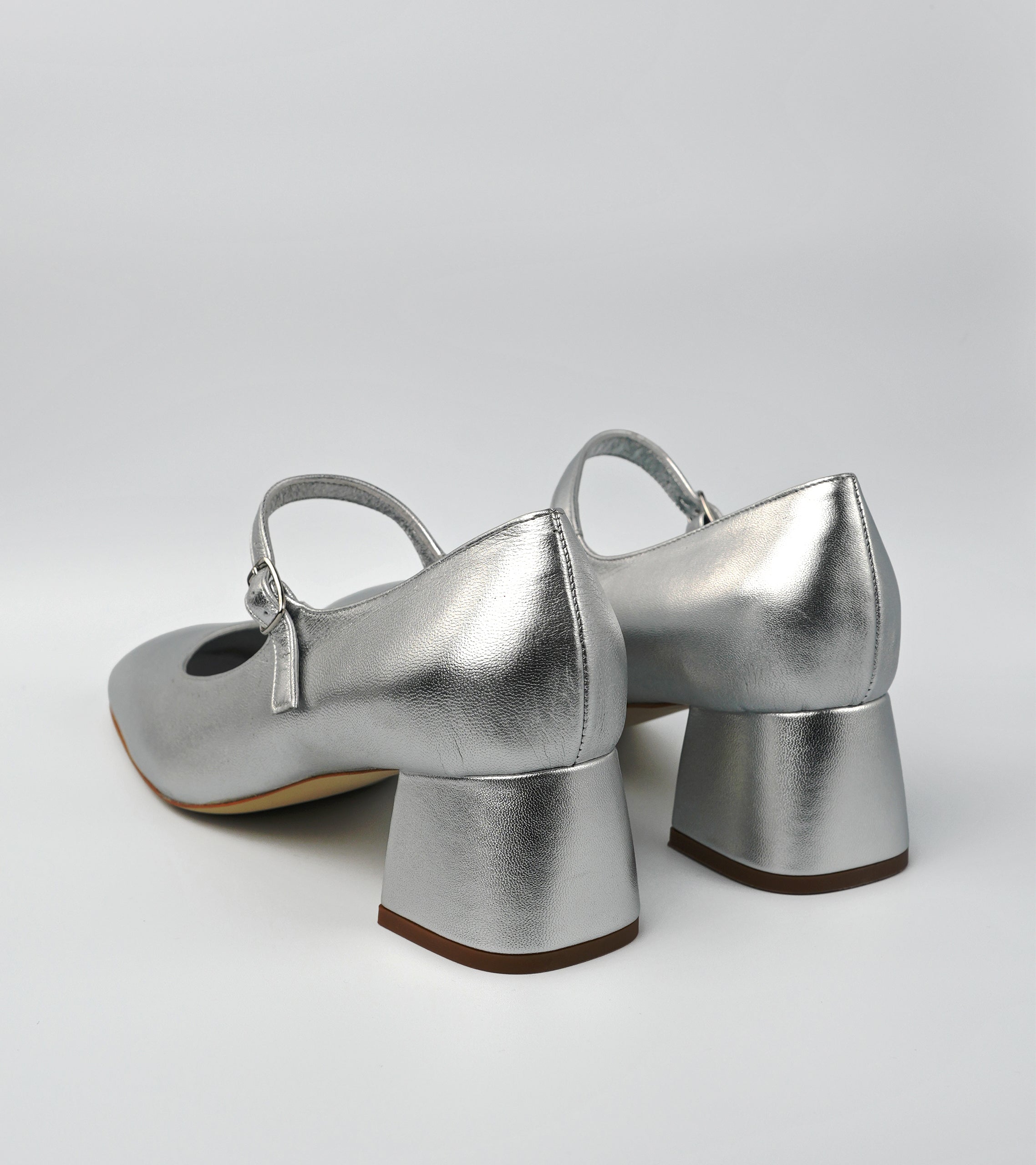 Pair of silver high-heeled shoes on a light gray background #color_napoli silver