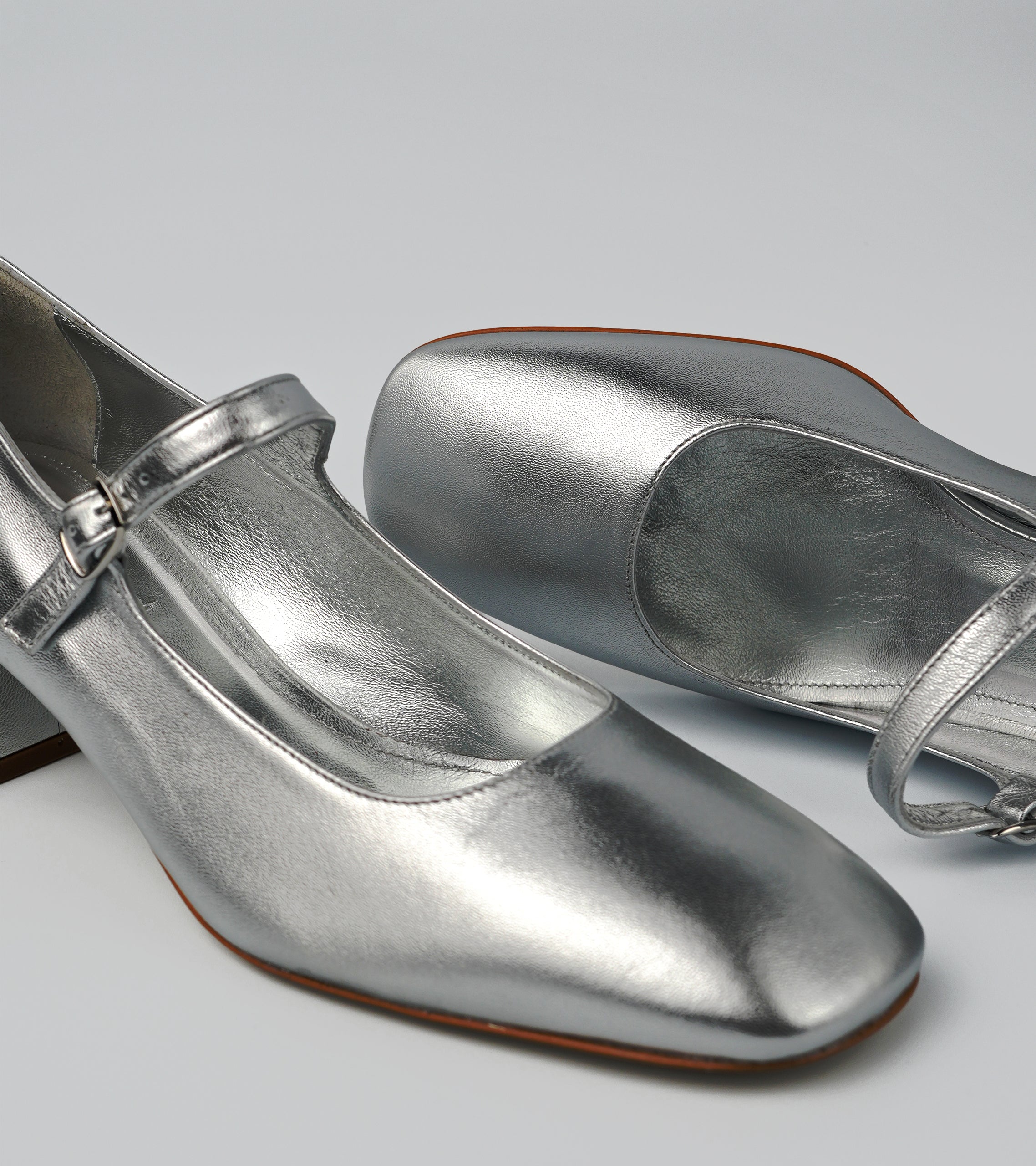 Pair of silver shoes with a strap on a light gray background #color_napoli silver