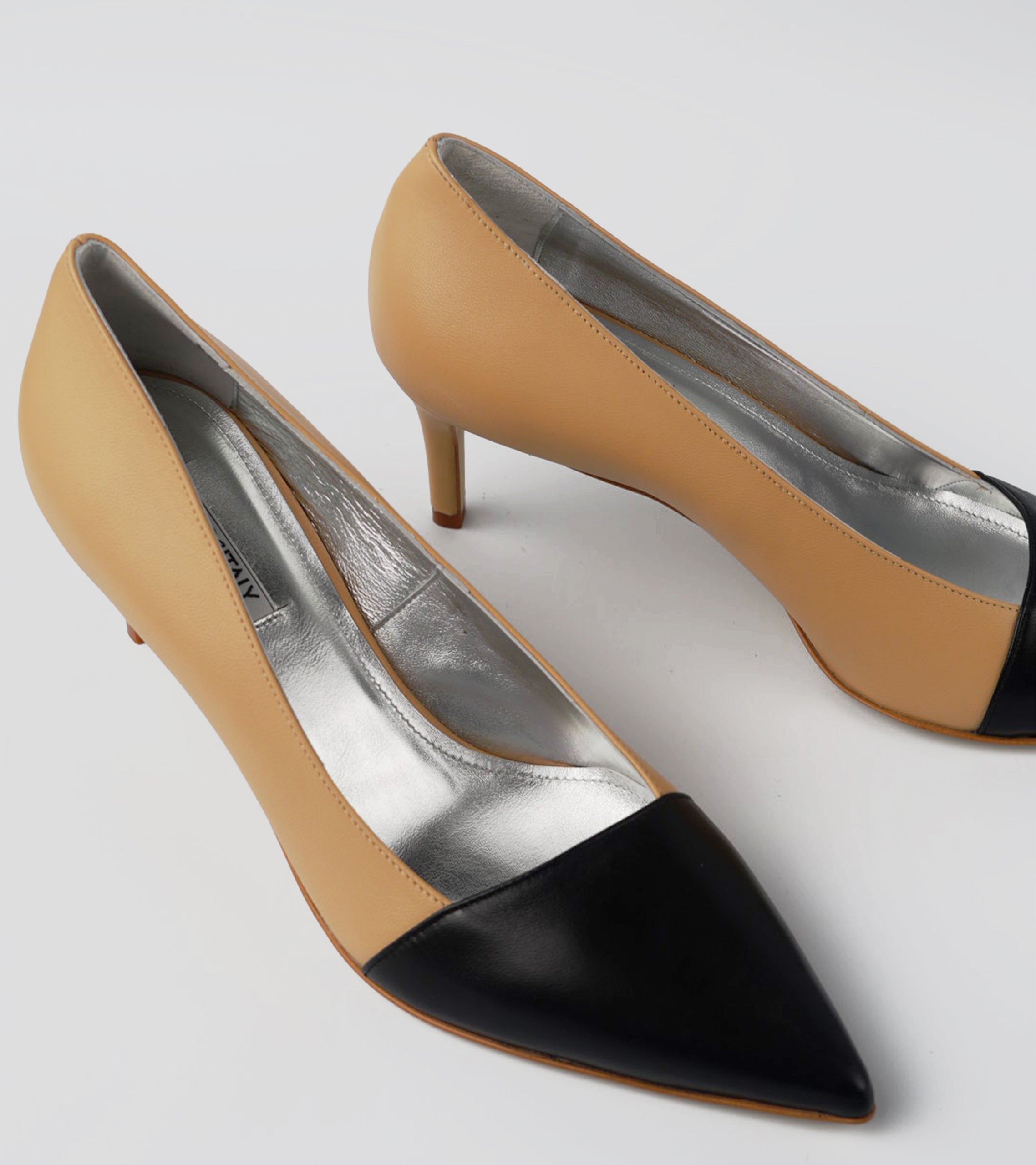 Pair of high-heeled shoes with black pointed toes on a light gray background #color_grosetto nude