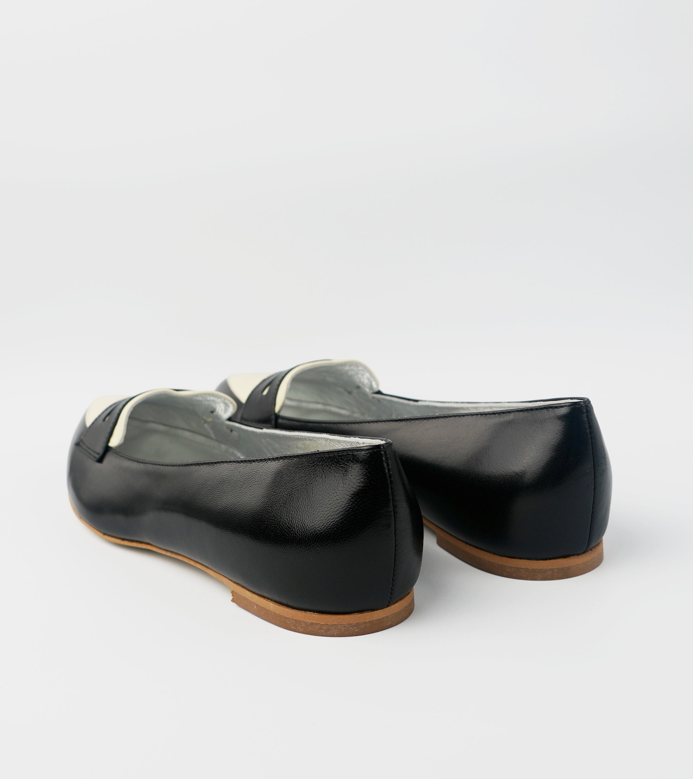 Pair of black shoes with brown soles on a light gray background #color_milano black amalfi white