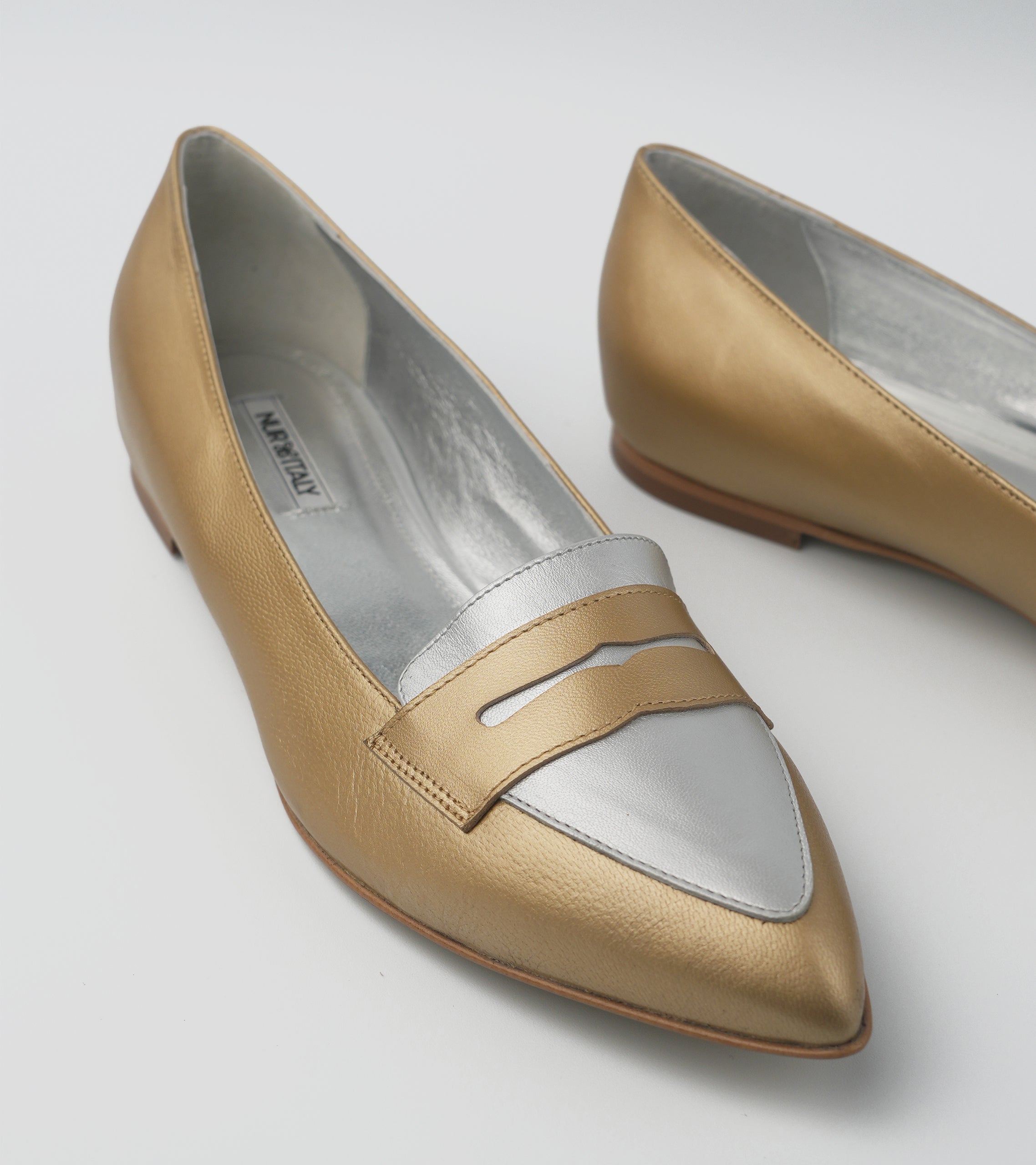 Pair of gold and white shoes on a light gray background #color_venezia gold napoli silver