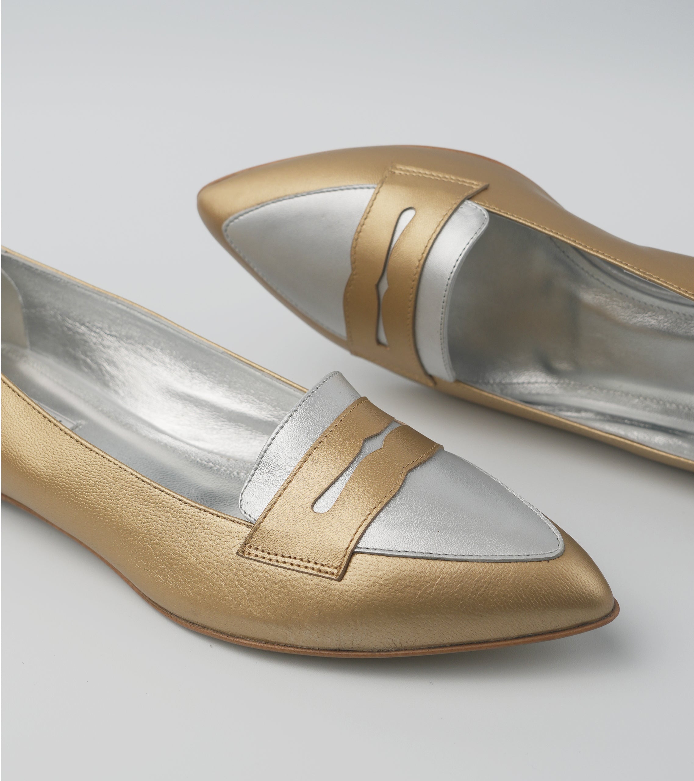 Pair of gold and silver pointed-toe shoes on a light gray background #color_venezia gold napoli silver