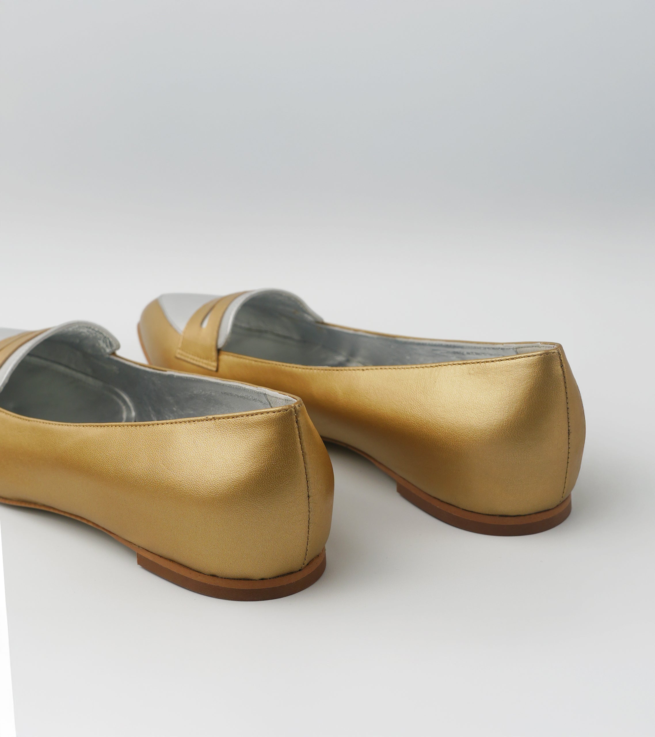 Pair of gold shoes on a white background #color_venezia gold napoli silver