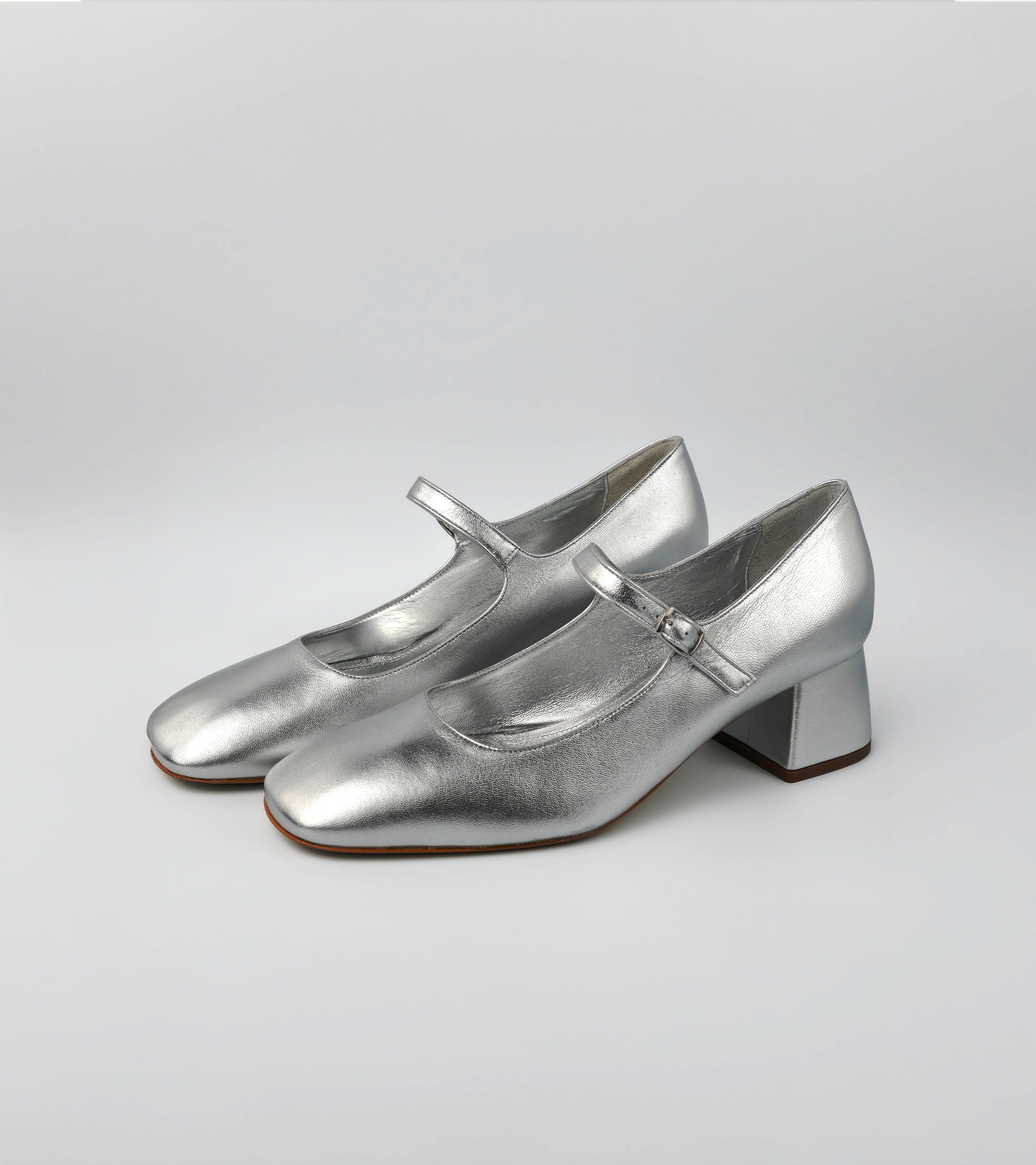 Pair of silver shoes with a block heel on a light gray background #color_napoli silver