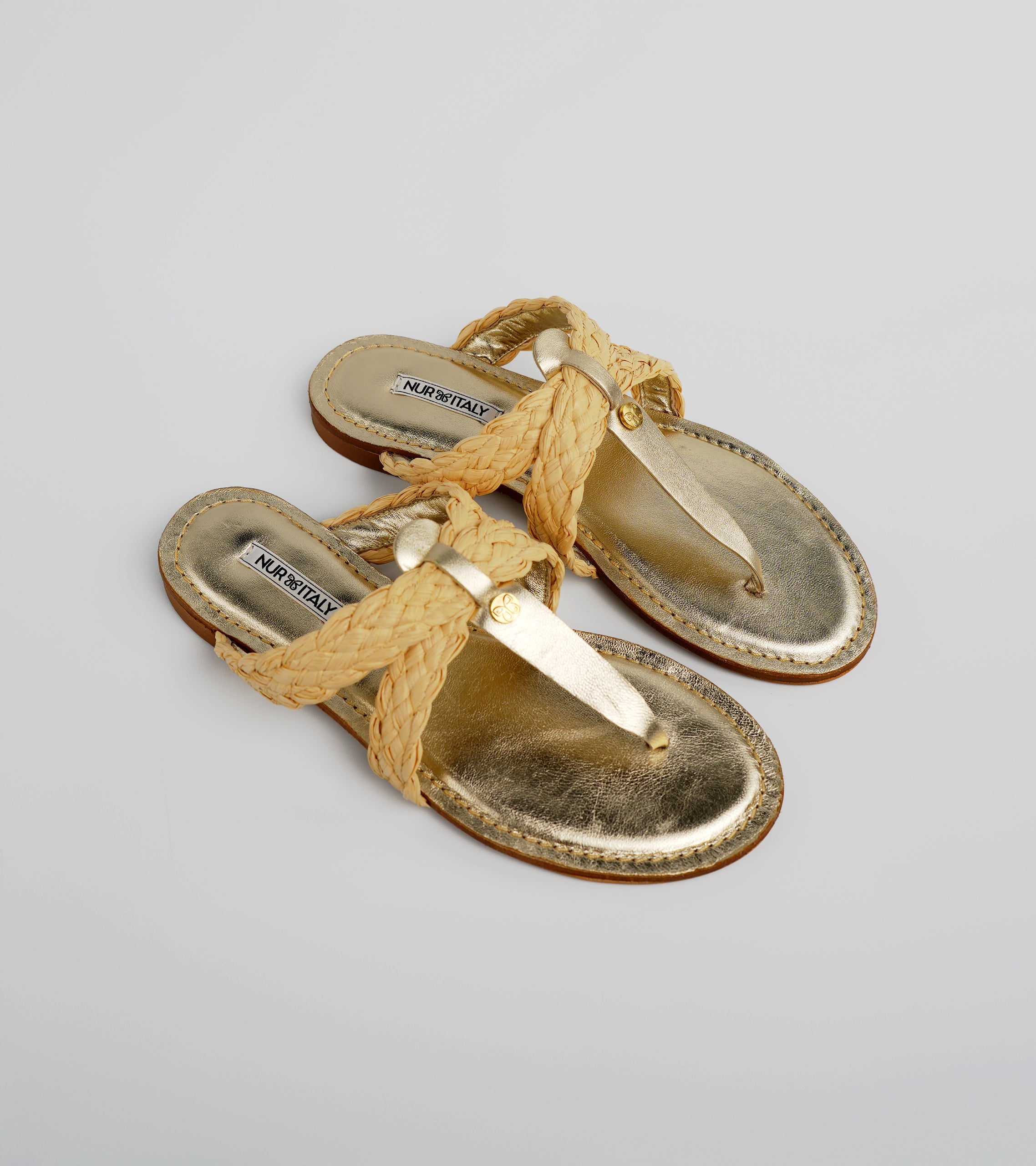 Pair of gold sandals with braided straps on a light gray background #color_venezia gold