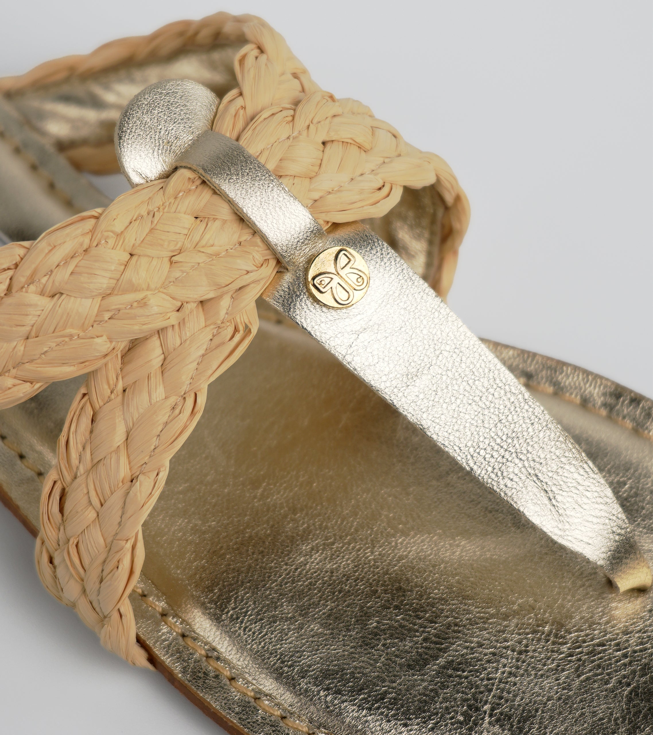 Gold sandal with braided strap and metallic finish on a neutral background #color_venezia gold