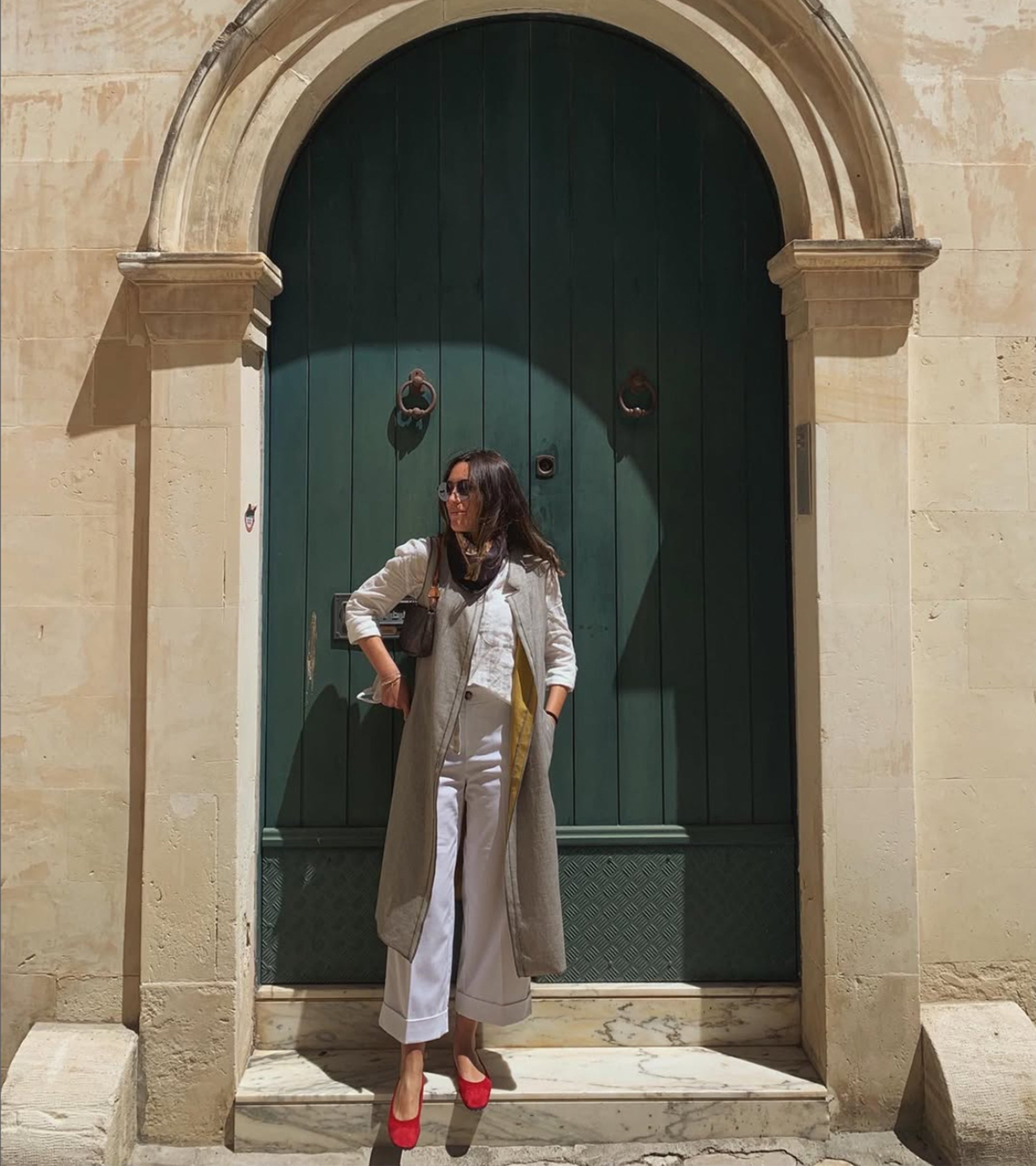 Woman standing in front of a large green door on a stone building #color_varese fire