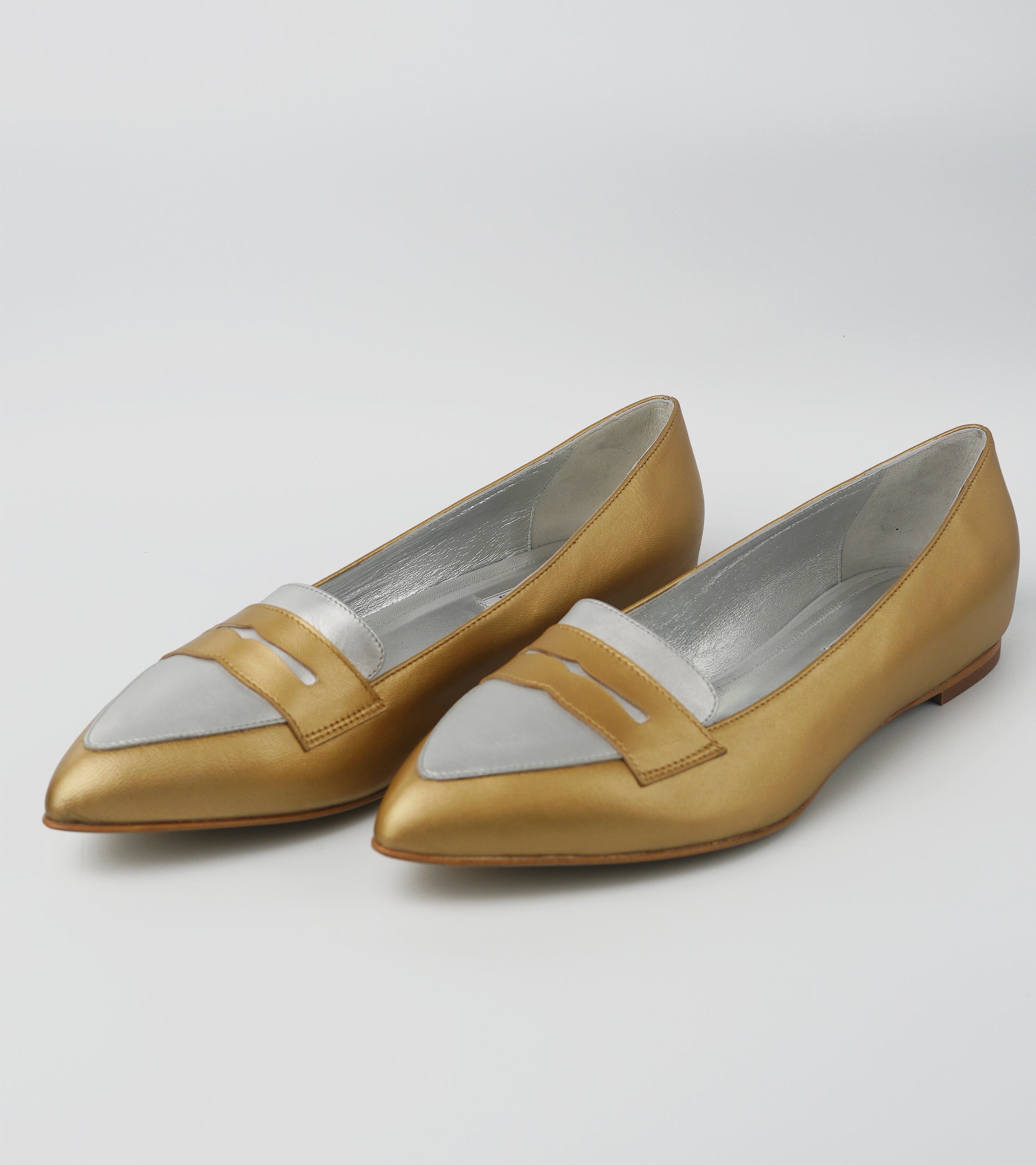 Pair of tan shoes with white accents on a light gray background #color_venezia gold napoli silver